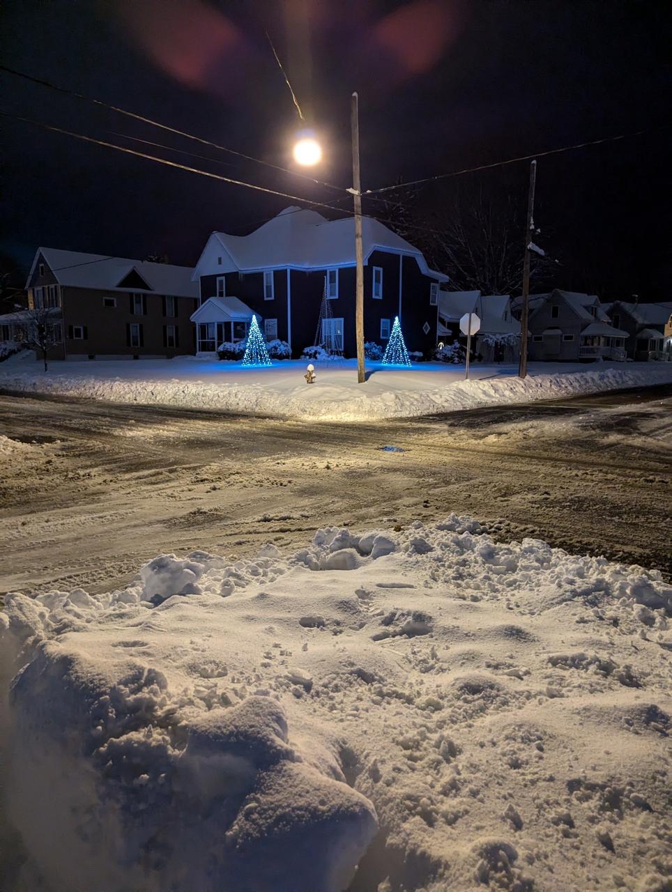 Two Christmas Corner displays glowing outdoors beside a snow-covered property